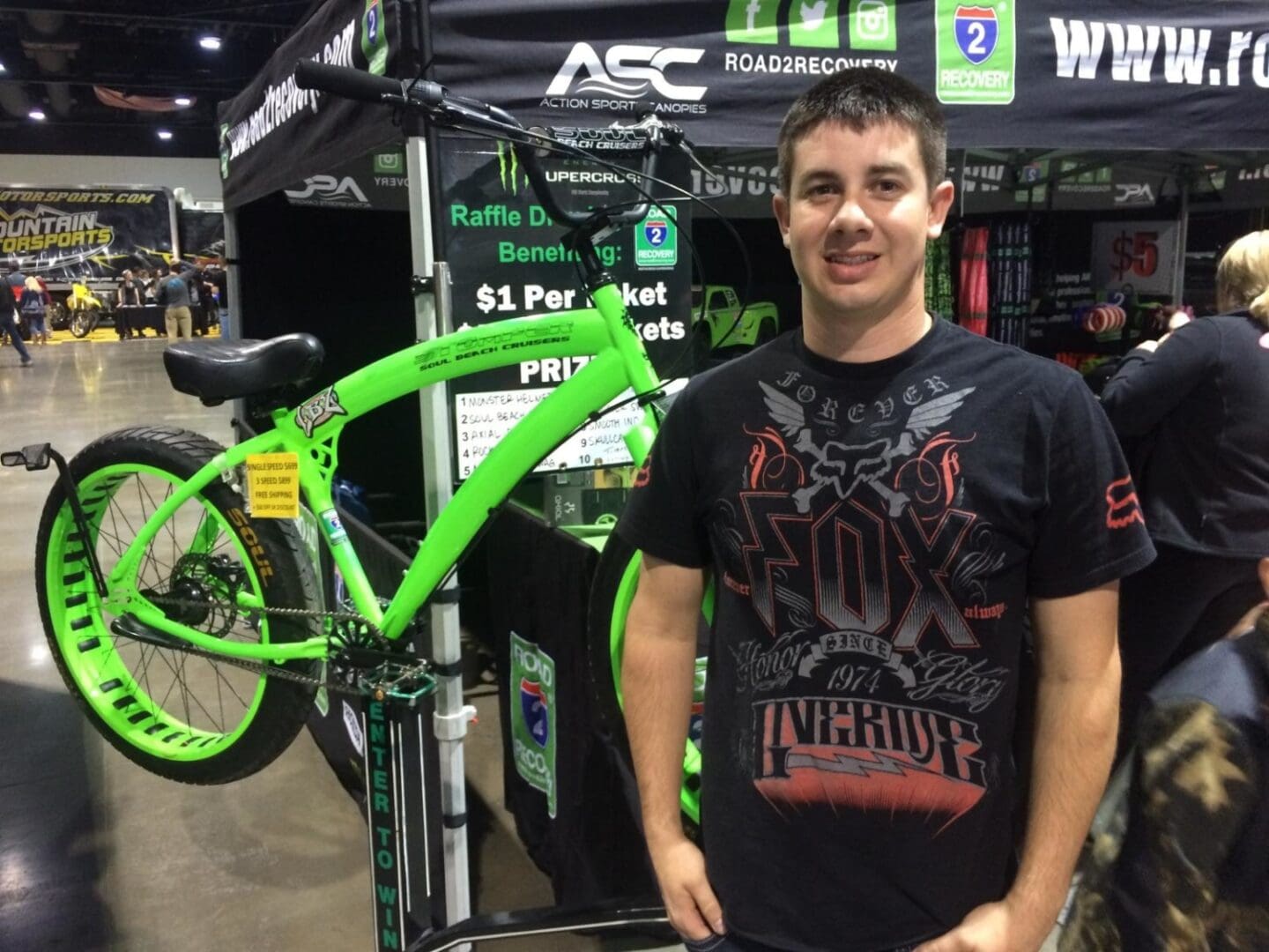 Man standing next to a green bicycle.
