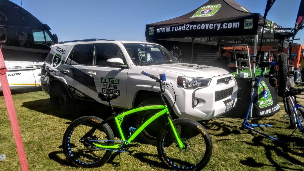 Bicycle and SUV at outdoor event display.