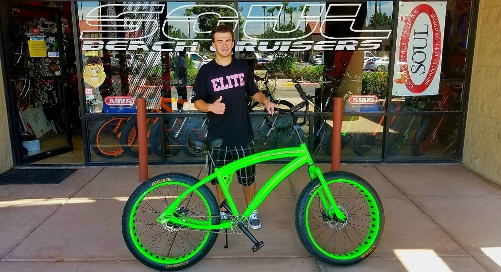 Person with bright green bicycle outside shop.