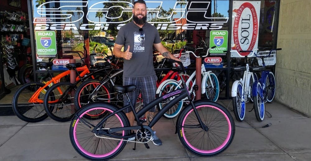 Man with bicycle in front of bike shop.