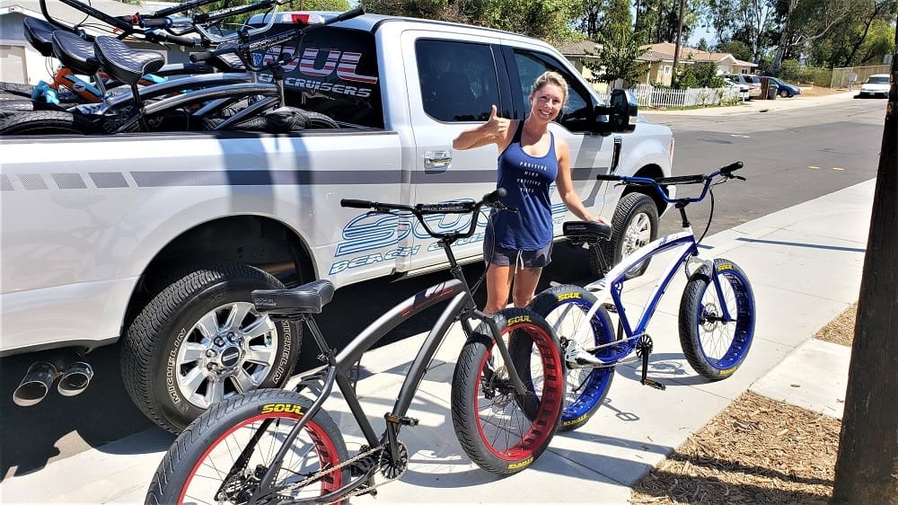 Woman with bicycles beside a parked truck.