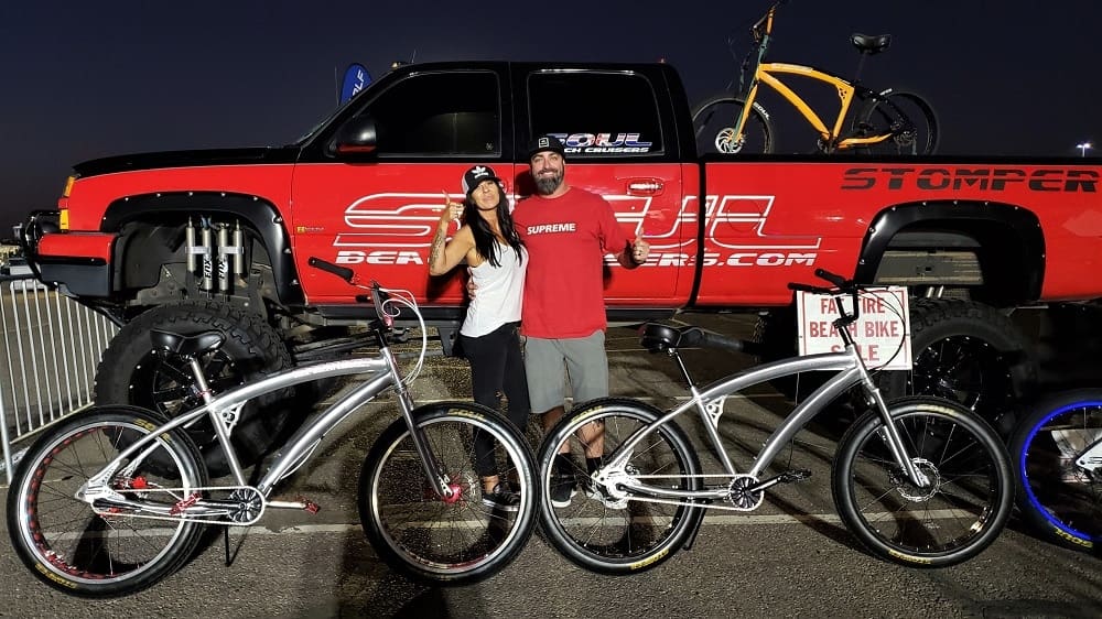 Couple posing with bicycles and red truck.