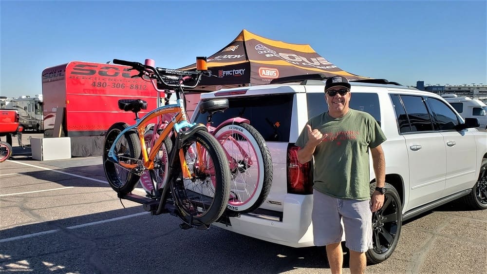 Man standing by SUV with mounted bicycles.