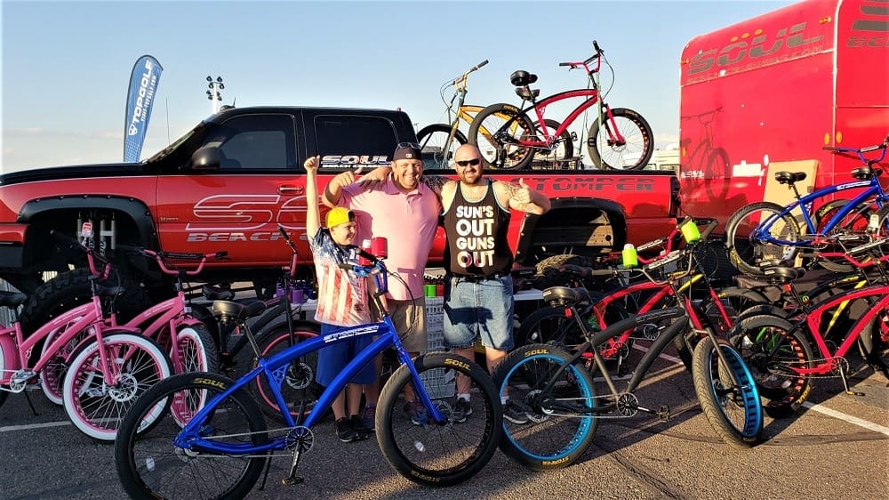 People posing with custom bicycles and truck.