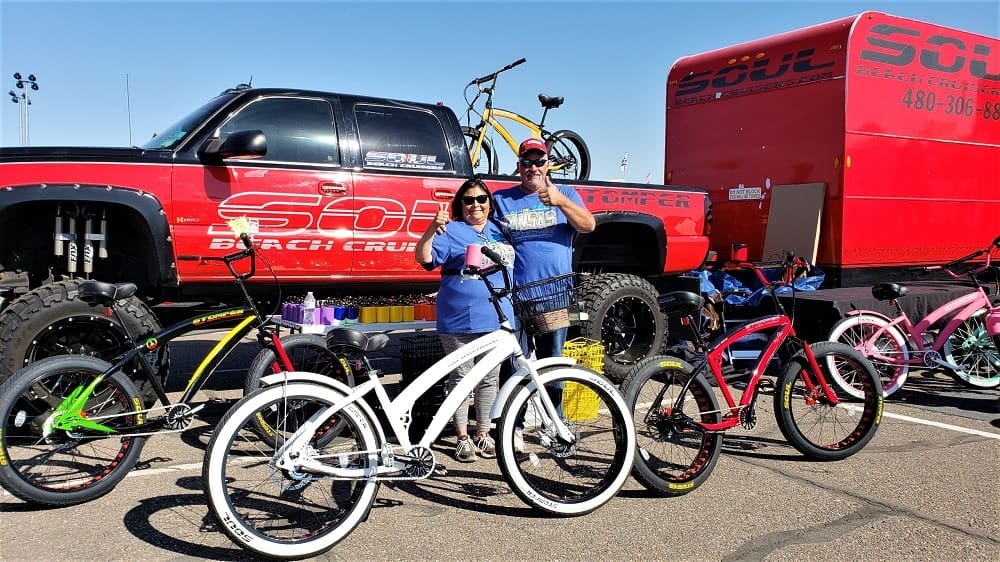 People standing with colorful bicycles and truck.