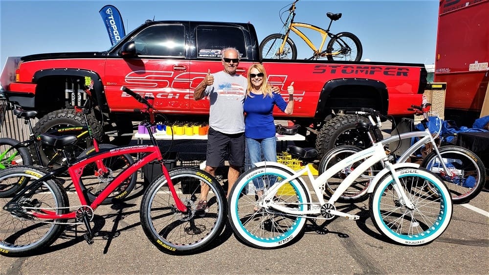 Two people posing with colorful bicycles.