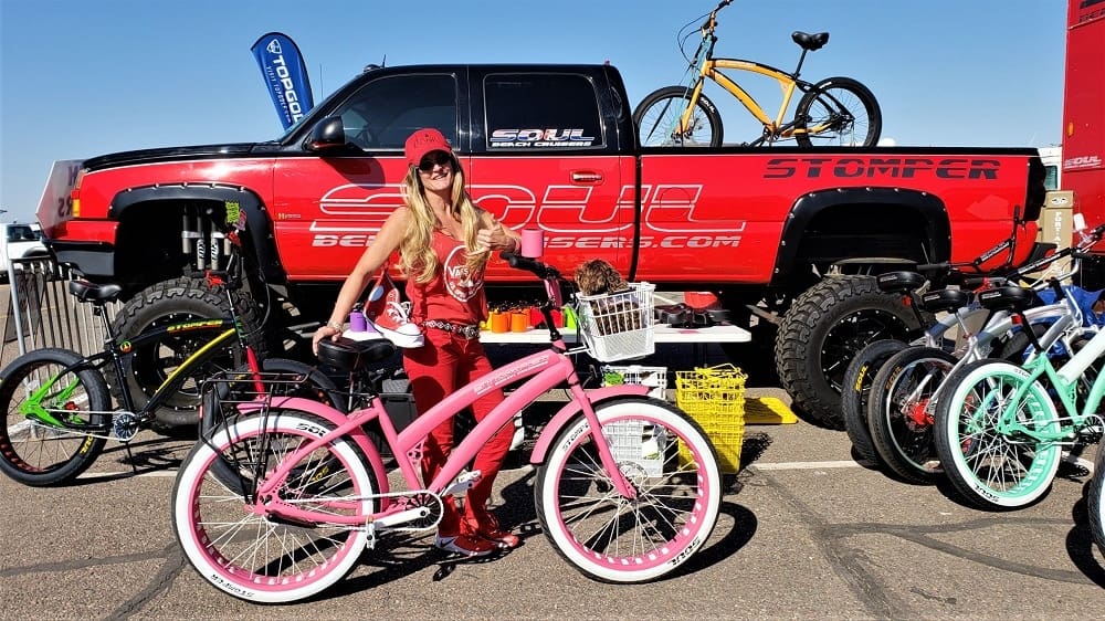 Person posing with pink bicycle, red truck.