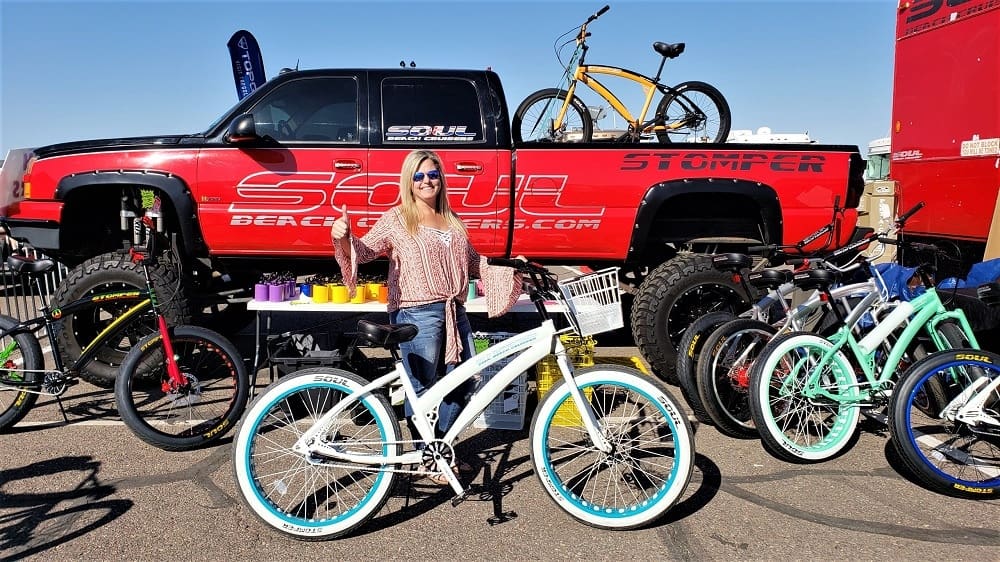 Woman posing with bicycles at outdoor event.