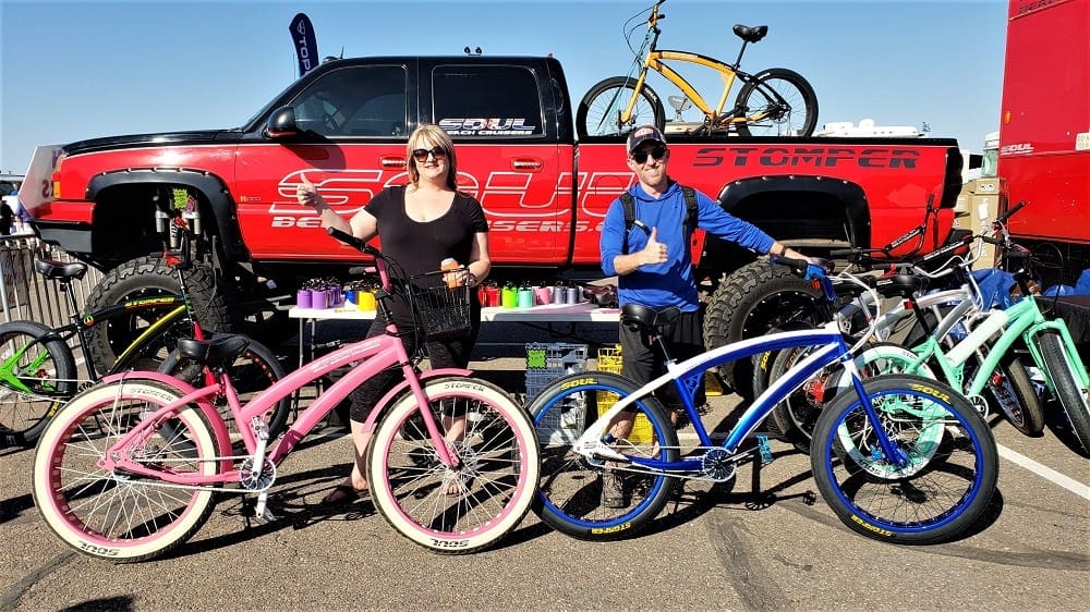 People posing with colorful bicycles and truck.