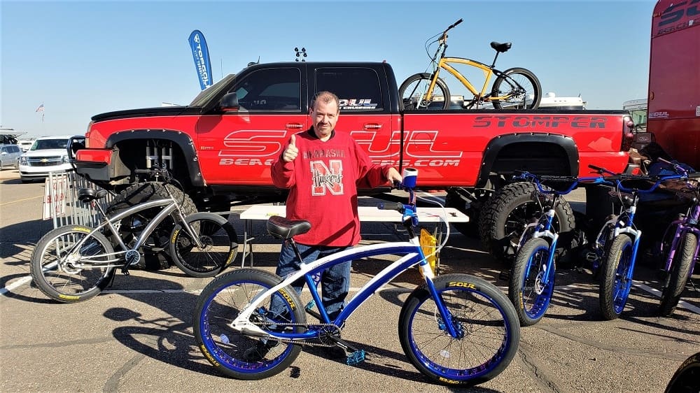 Man posing with bicycle in front of truck.