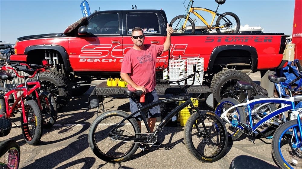 Man displaying bicycles in front of truck.