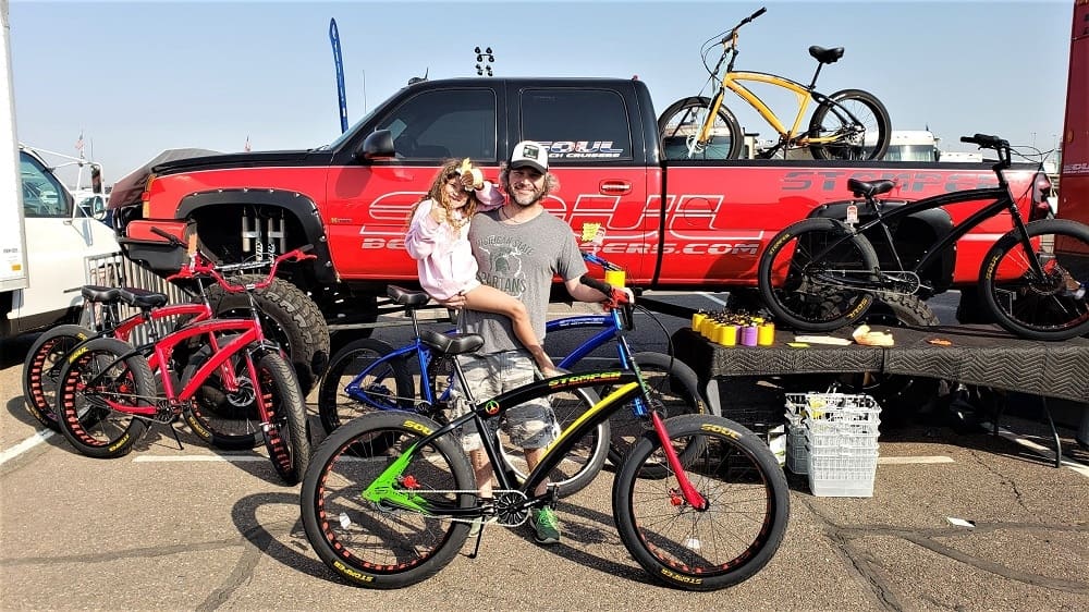 Man and child with colorful bicycles displayed.