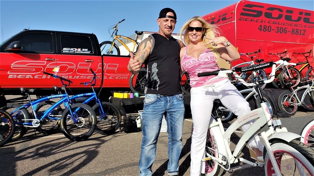 Man and woman posing with bicycles outdoors.