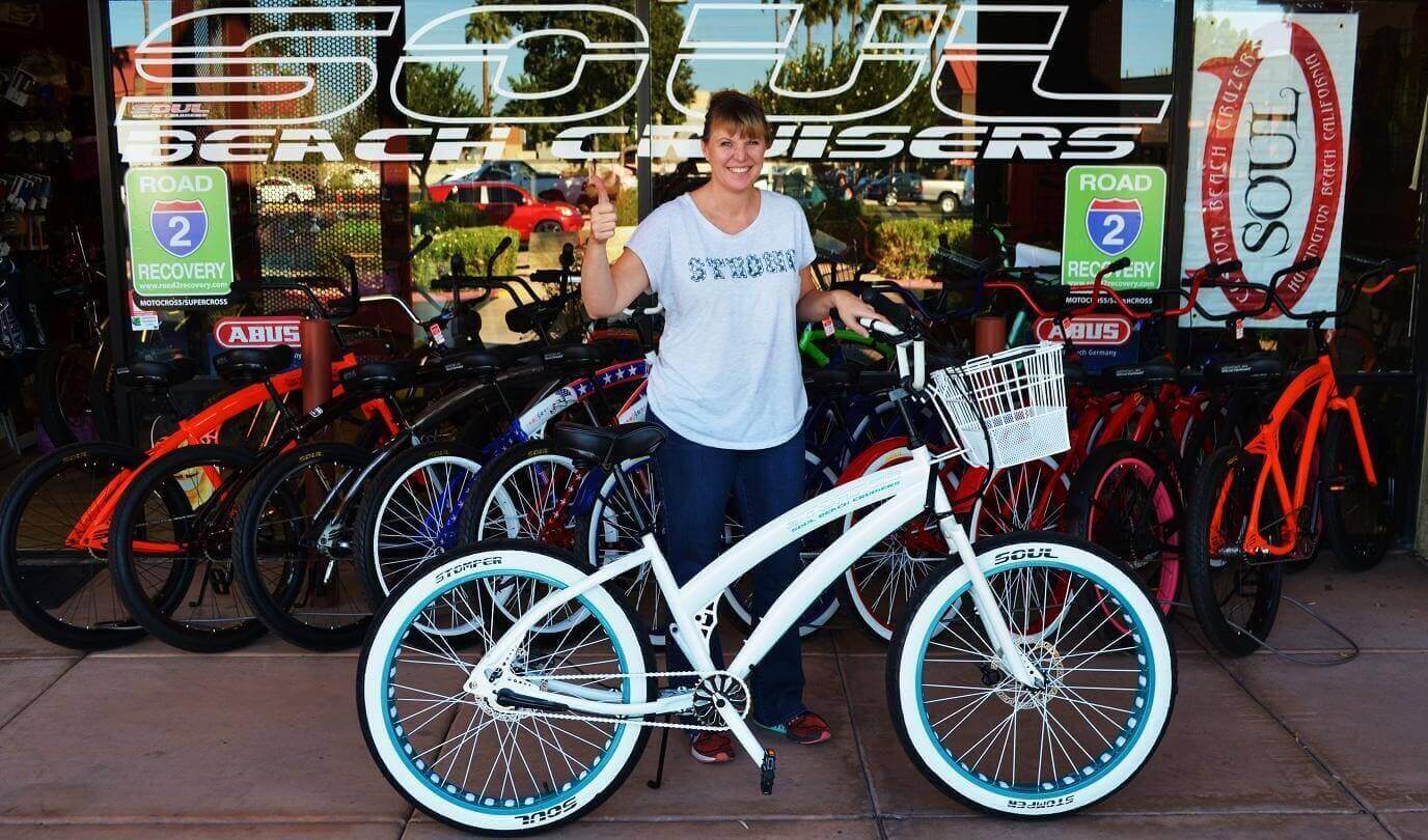 Person with white bicycle at bike shop.