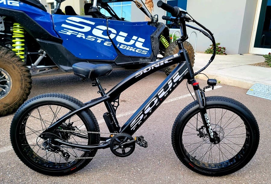 Black electric bike parked near blue vehicle.