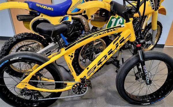 Yellow bicycle and motorcycles in a showroom.