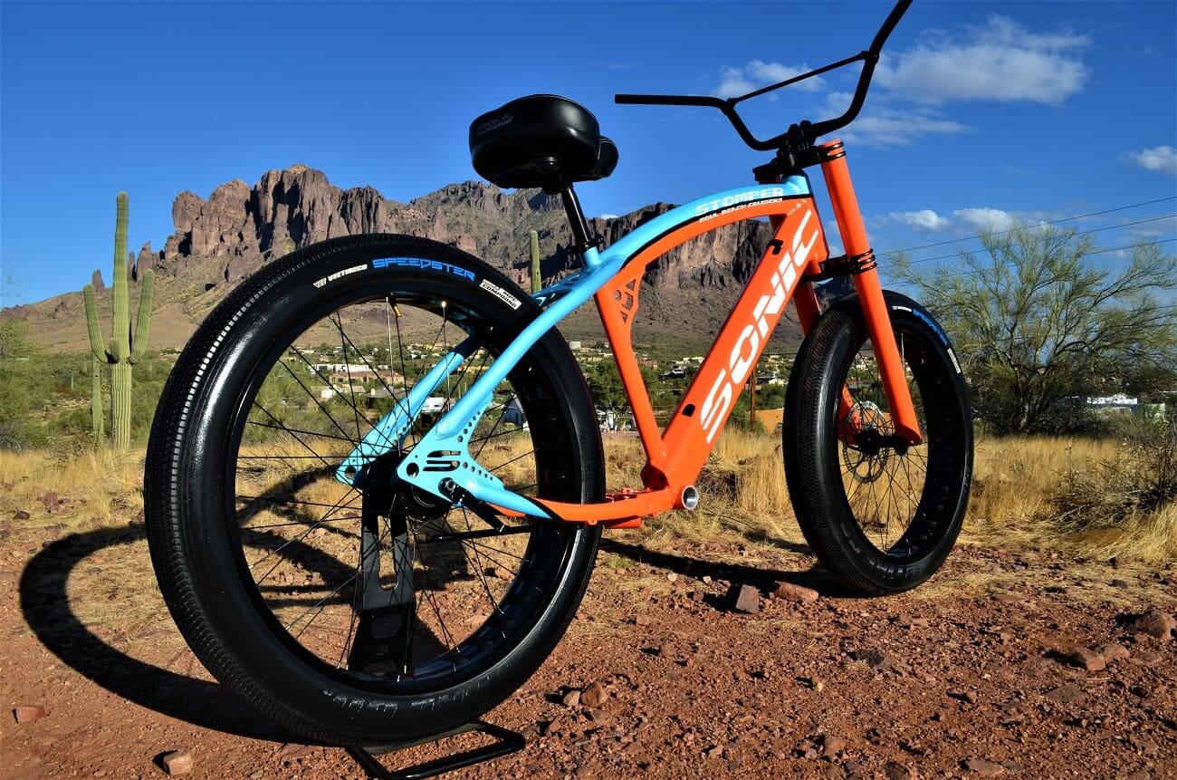 Orange and blue bicycle in desert landscape.