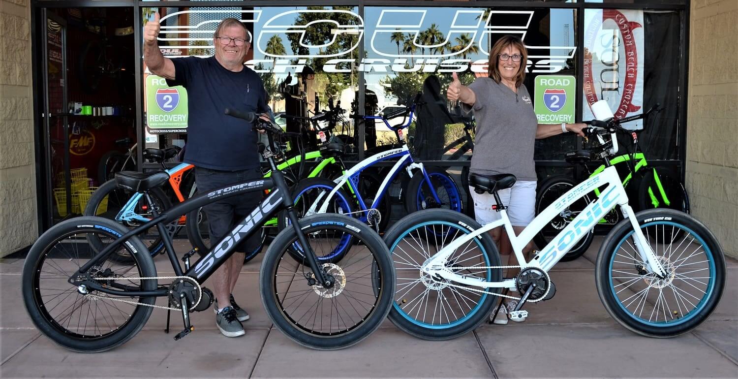 Two people with bicycles outside a shop.