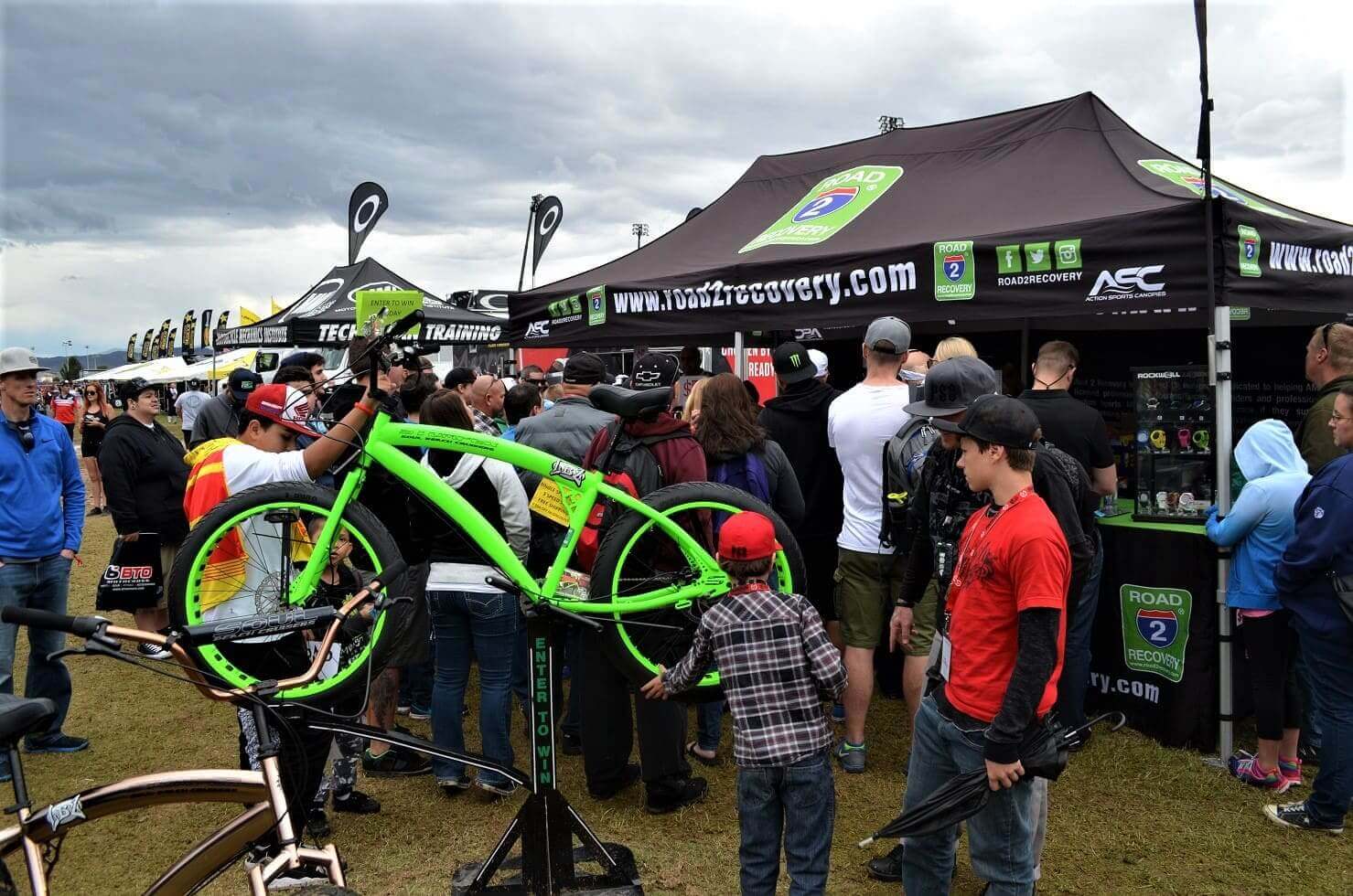 People gathered at outdoor bike event tents.