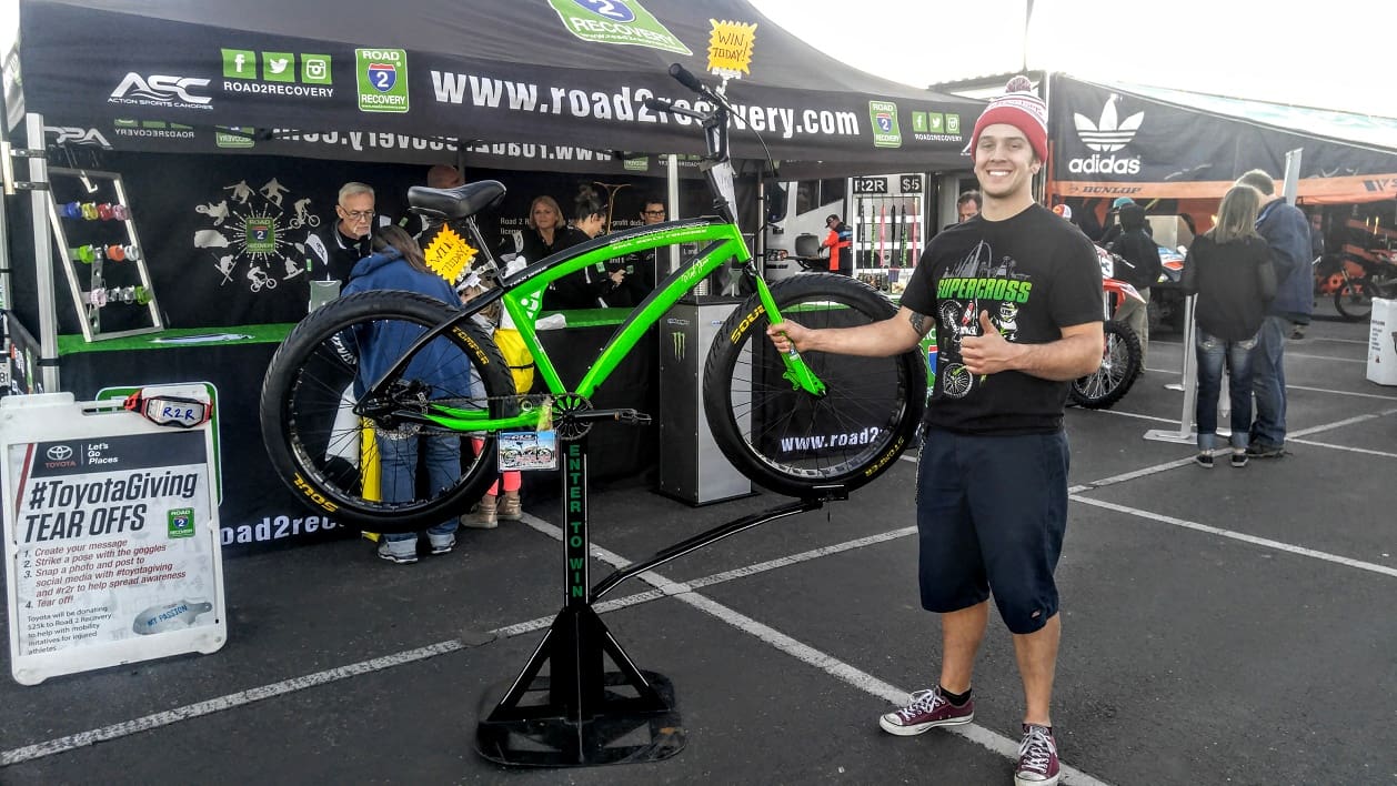 Man smiling next to green bicycle display.