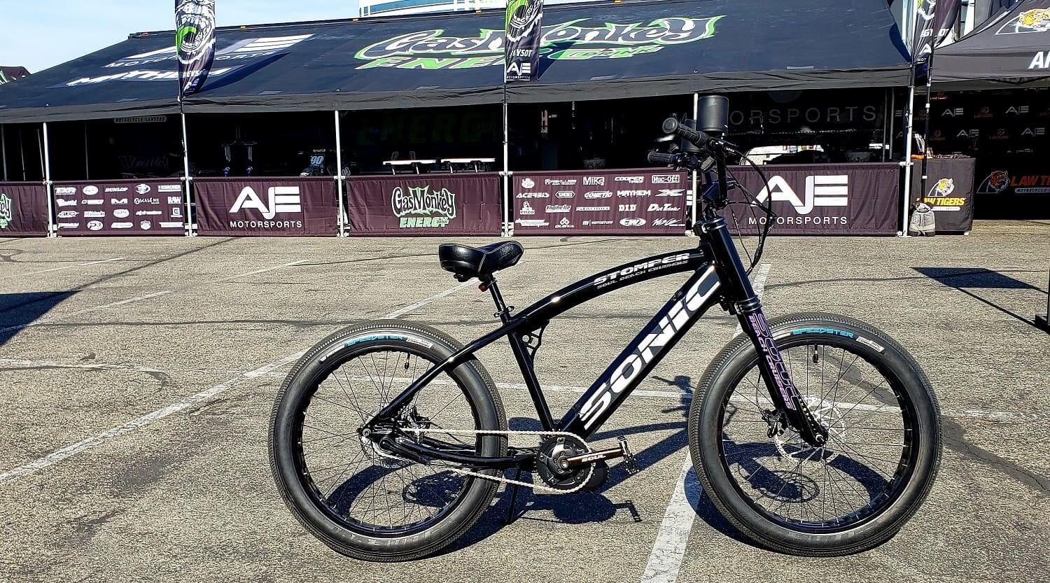 Black electric bike parked on asphalt pavement.
