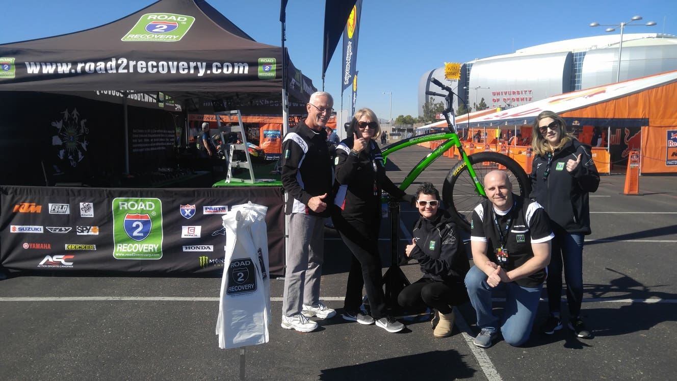 Group posing with bicycle at outdoor event.