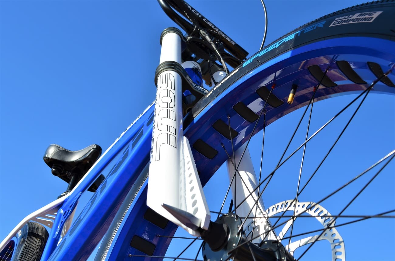 Blue bicycle with disc brakes, low angle.