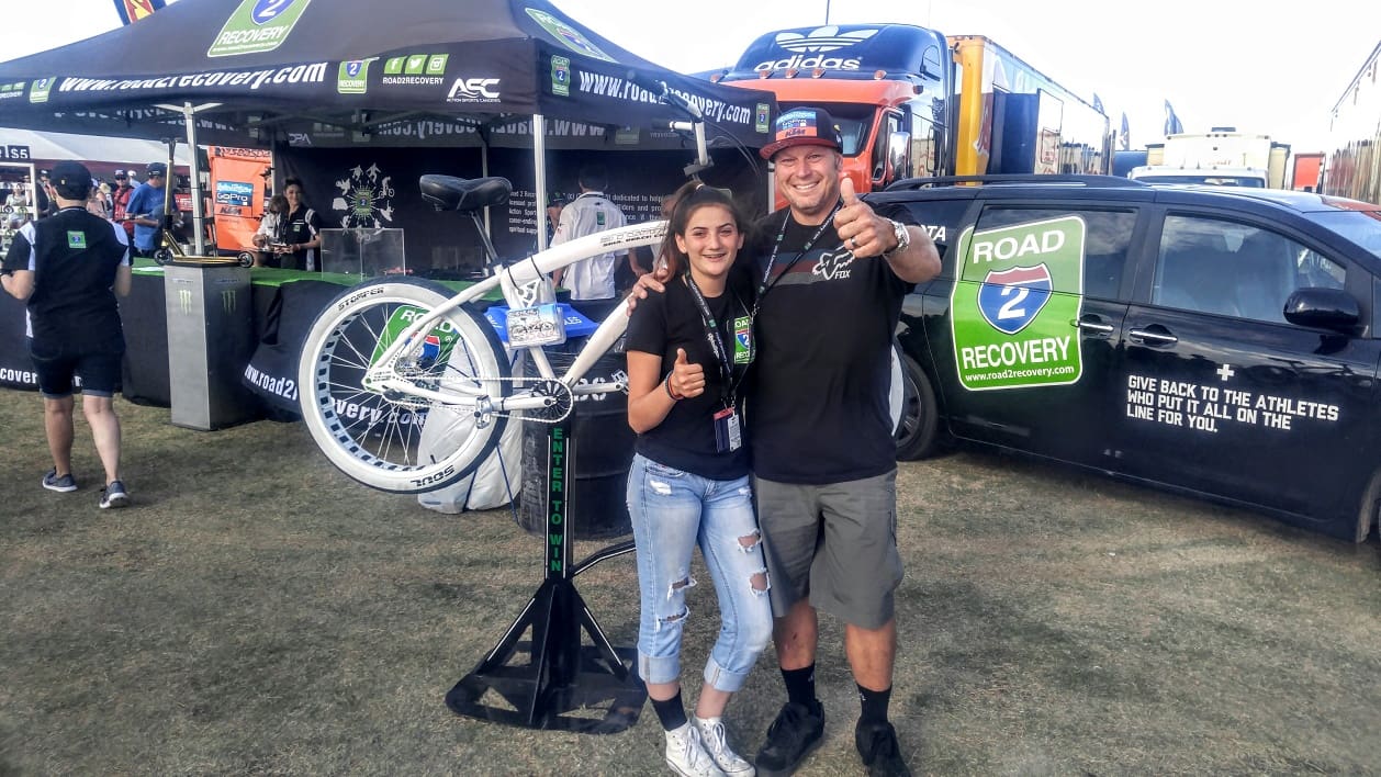 Two people smiling, posing by bicycle stand.