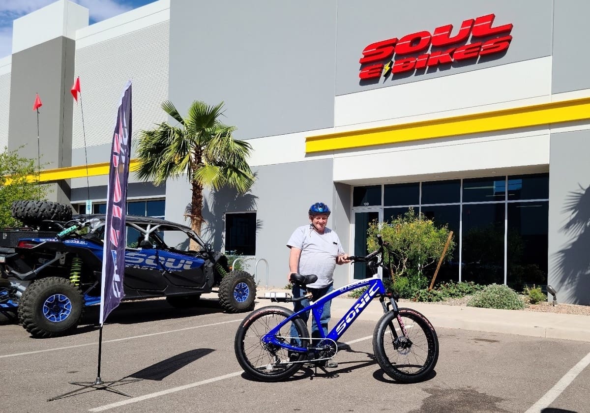 Man standing with bicycle in front of store.