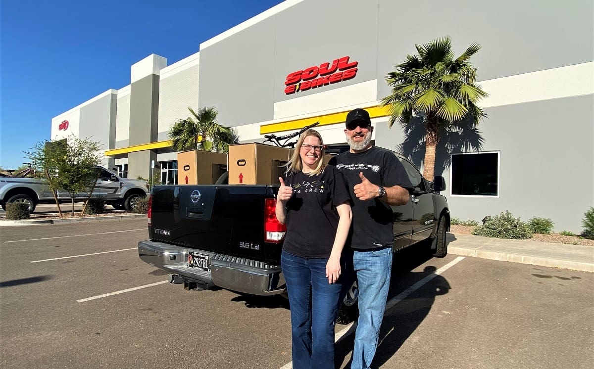 People smiling with thumbs up near truck.