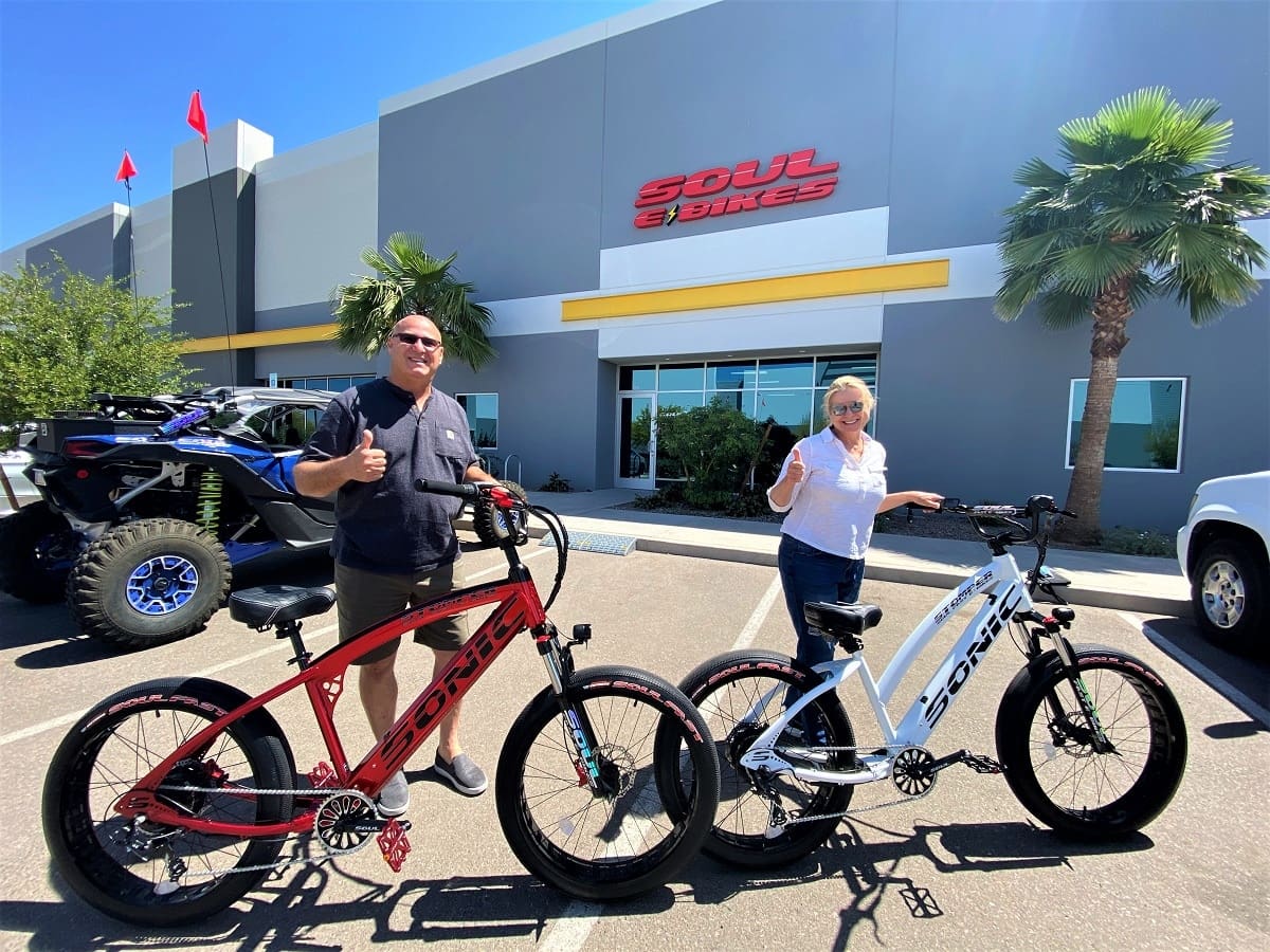 Two people with bikes in front of store.