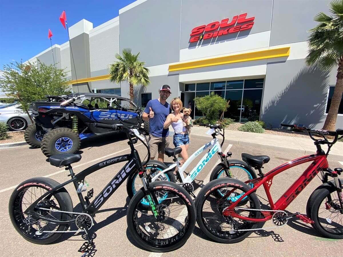 People with bicycles in front of store.