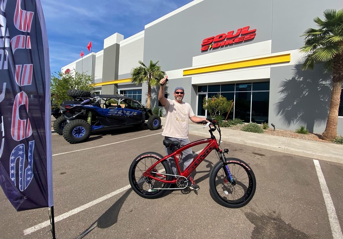Man with red bicycle outside a store.