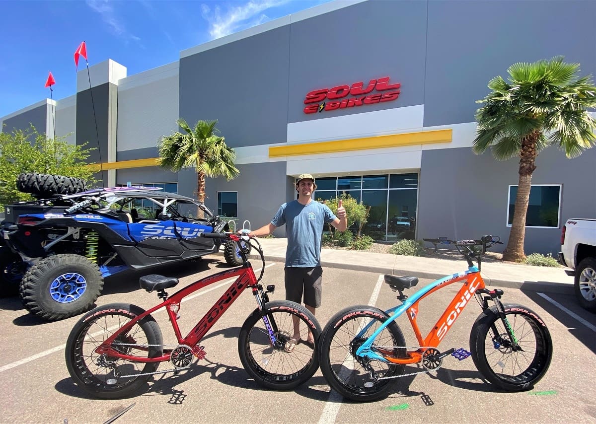 Man standing with two colorful bicycles.