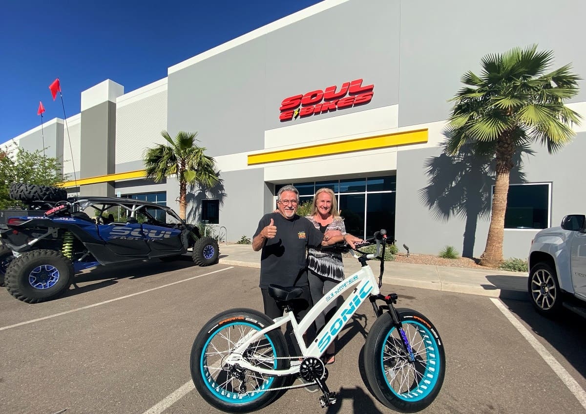 Two people with a bike outside building.