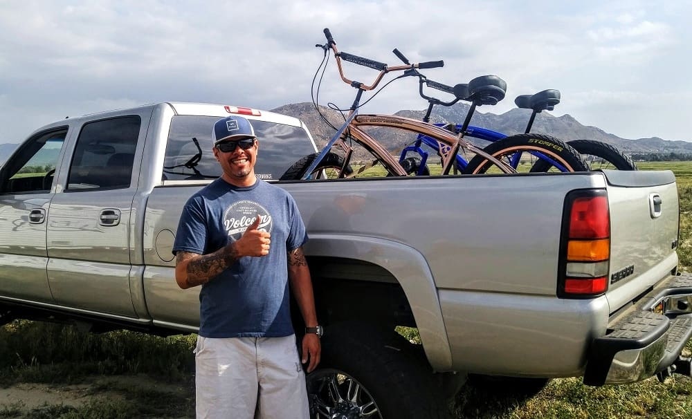 Man smiling beside truck with bicycles loaded.