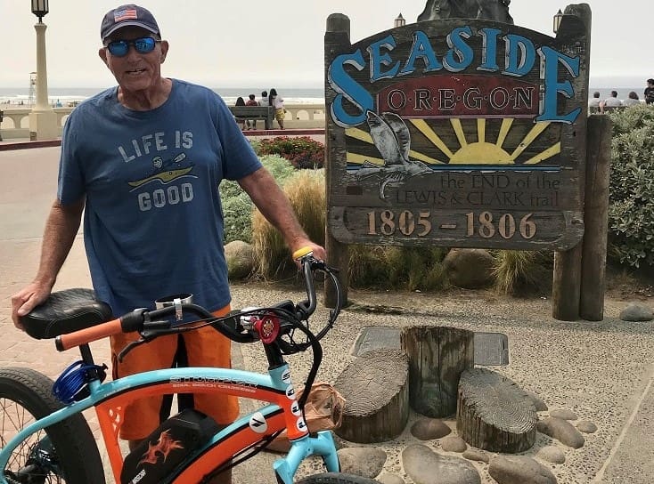 Man with bike near Seaside, Oregon sign.