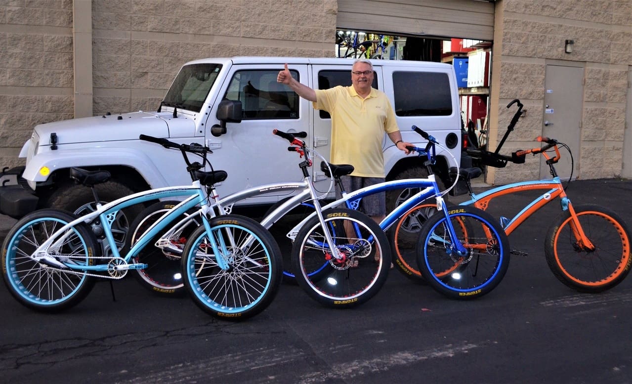 Man posing with bicycles and white SUV.