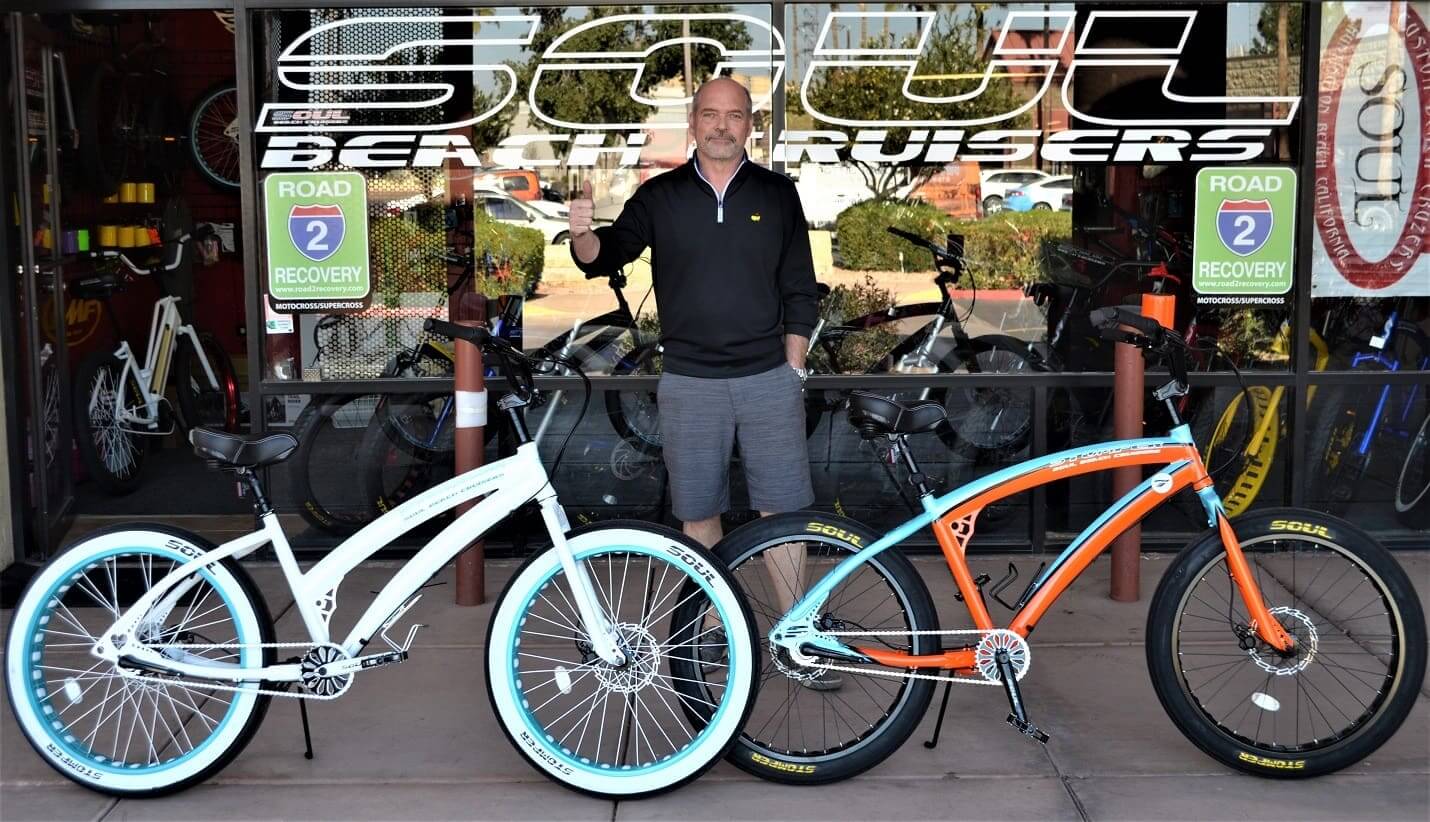 Man standing with two colorful bicycles.
