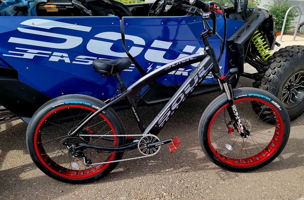 Black bicycle with red rims beside vehicle.
