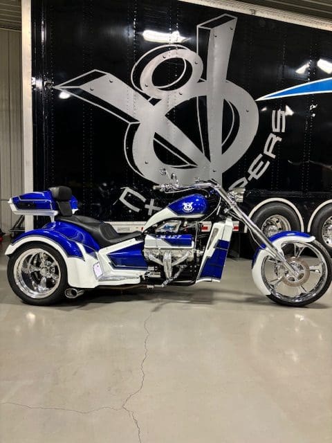 Blue and white custom trike motorcycle parked.