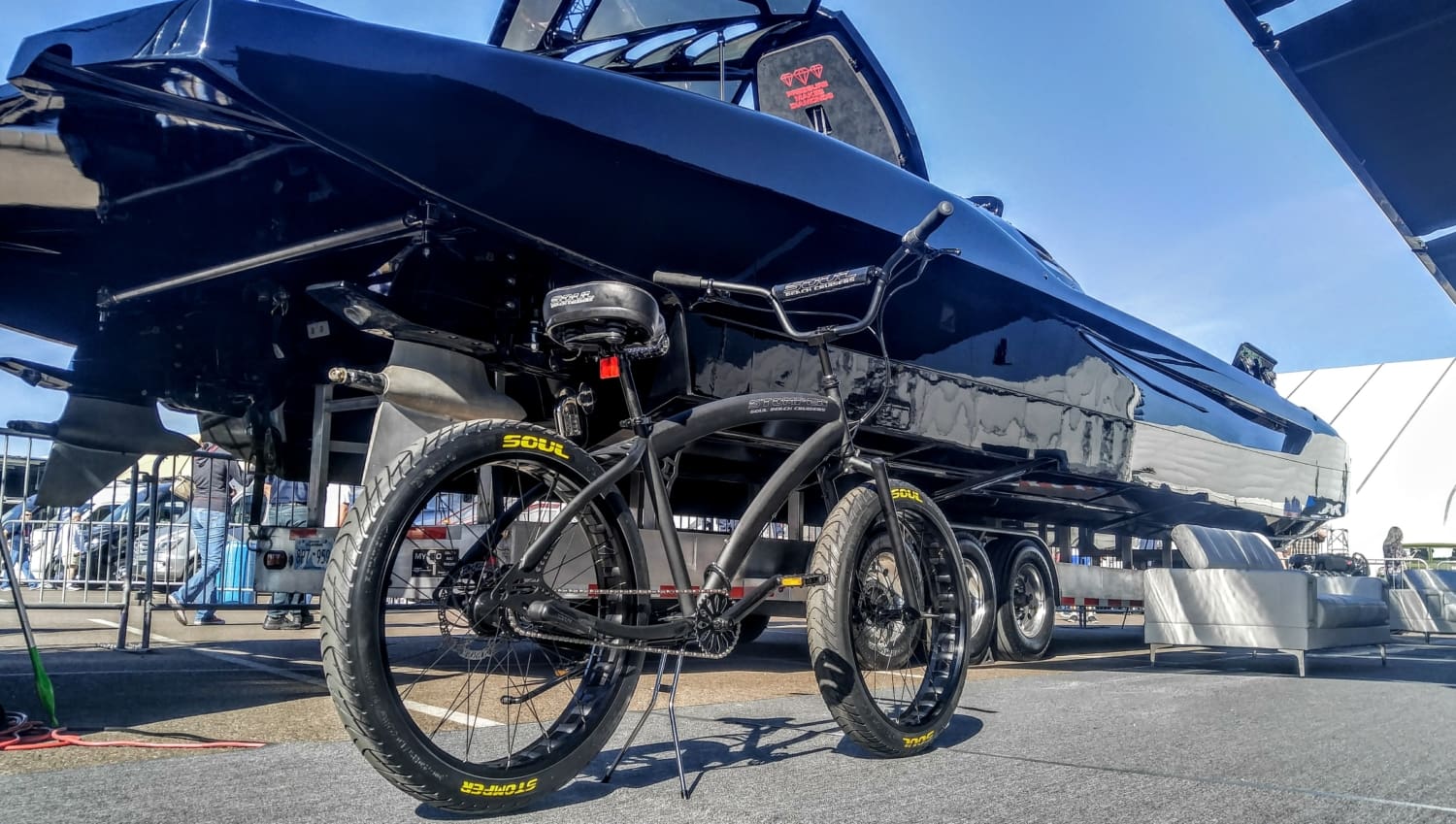 Bicycle parked beneath large black boat outdoors.