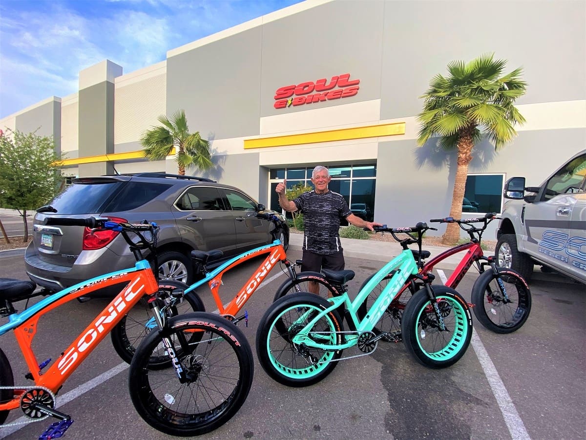 Man with colorful bikes outside Soul Bikes shop.