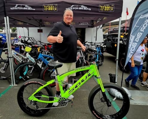 Man posing with bright green bicycle outdoors.