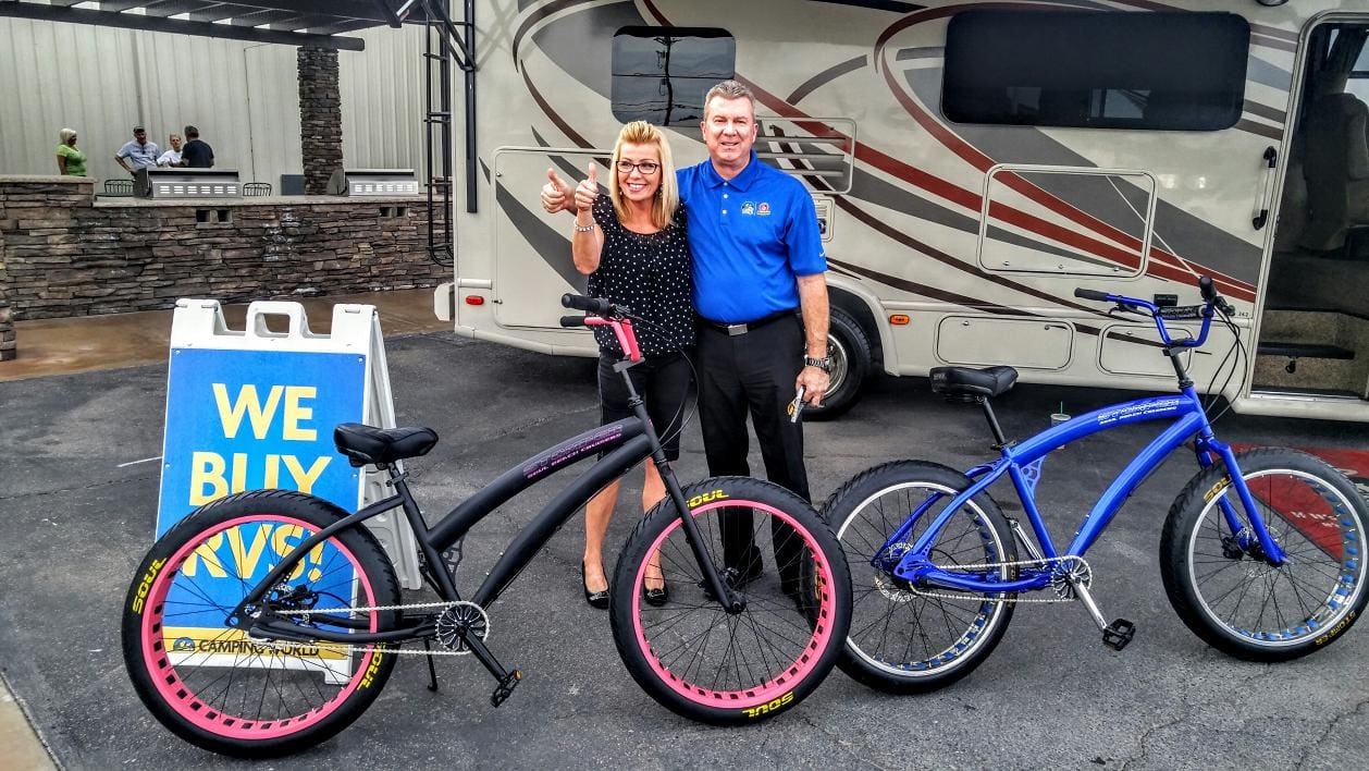 Couple standing with bicycles in front of RV.