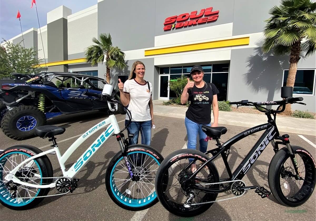 Two people with bikes outside a store.