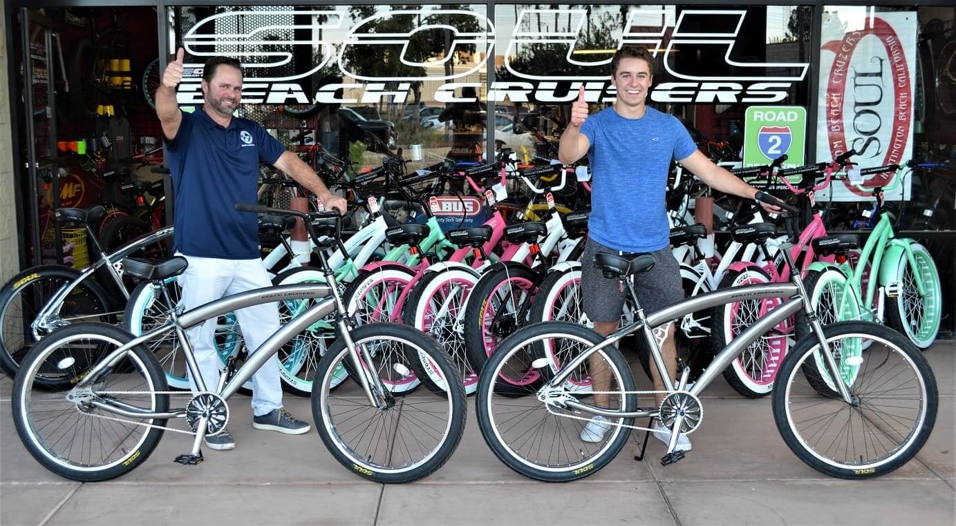 Two people with bicycles outside bike shop.
