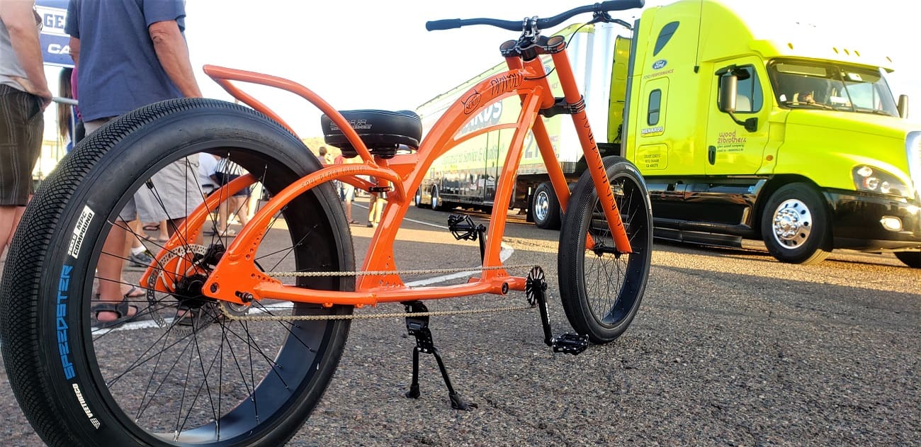 Orange bicycle and yellow truck on road.