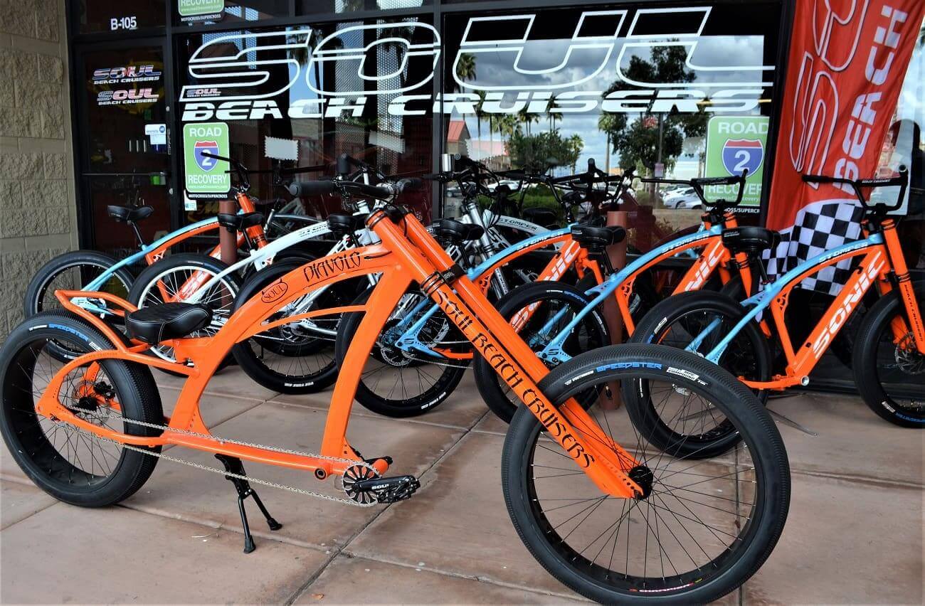 Orange custom bicycles displayed outside a store.
