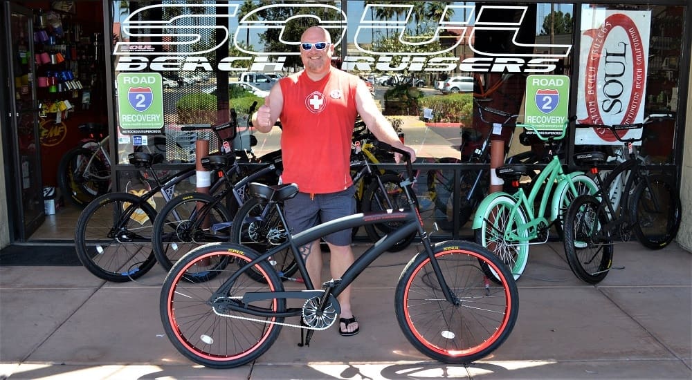 Man with bicycle outside bike shop.